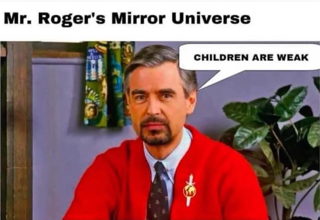 A man resembling Mr. Rogers, wearing a red cardigan over a collared shirt and tie, with a small pin on his left lapel…