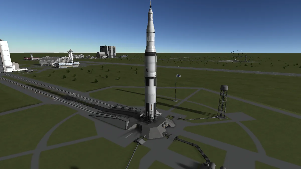 A computer-generated image of a tall, white and black rocket standing on a launchpad surrounded by roads, buildings, and…