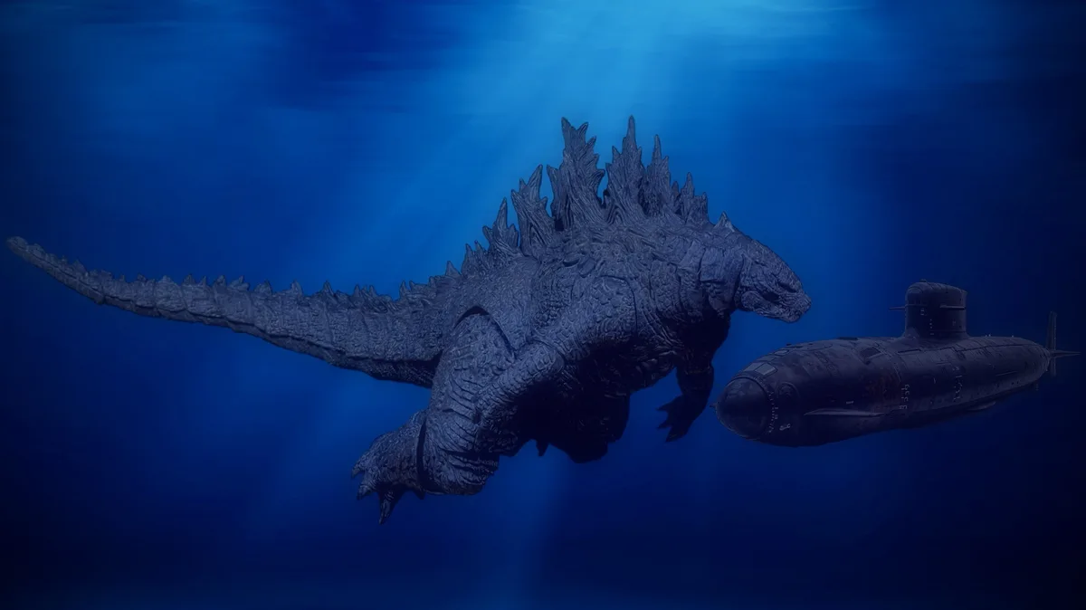 A large, dark grey Godzilla swims underwater next to a dark submarine in deep blue ocean water. The overlaid text reads…