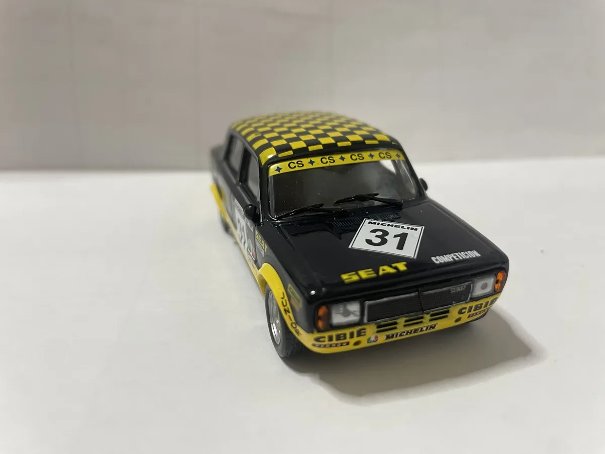 A black and yellow scale model of a SEAT rally car with checkered roof, number 31, and sponsor decals like Michelin and…