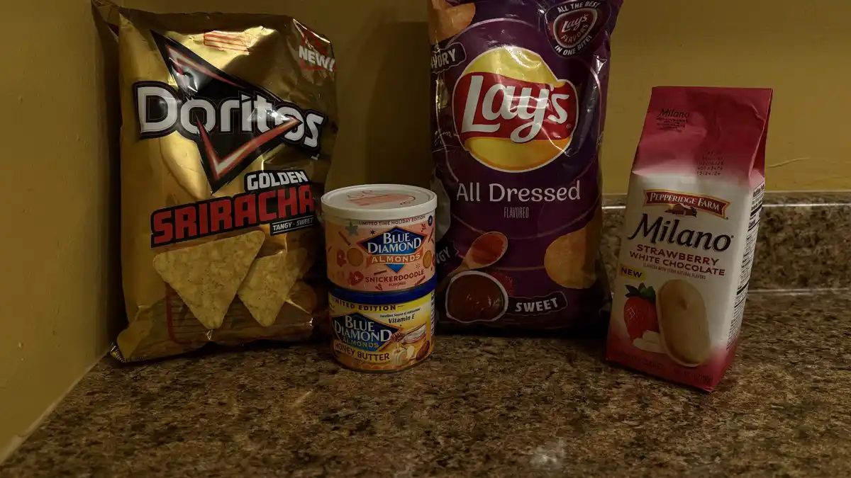 A countertop displays four snack items: a bag of Doritos Golden Sriracha, a bag of Lay's All Dressed, a bag of Pepperidge…