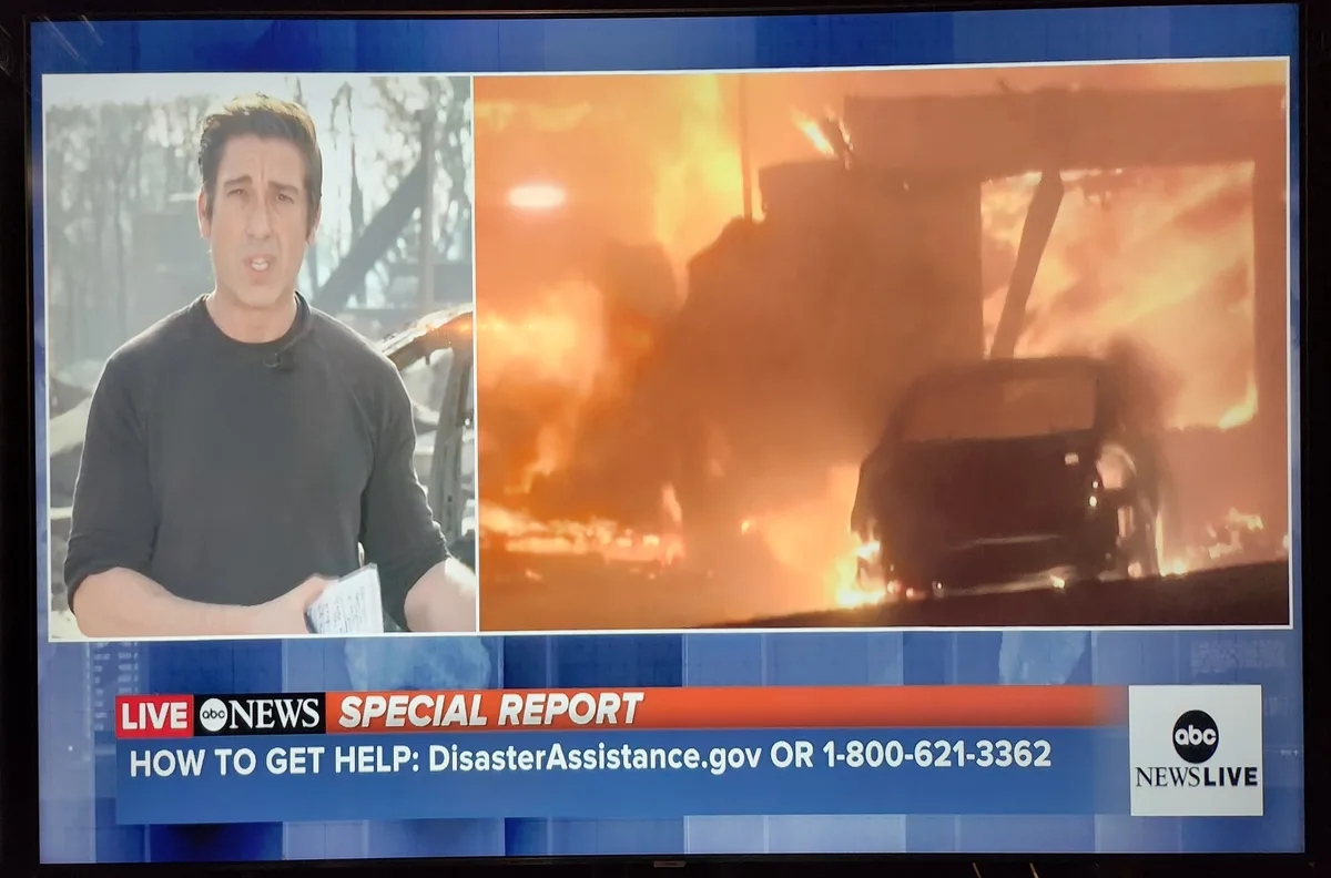 A split-screen abc news broadcast shows a male reporter on the left looking concerned while a large fire engulfs a building…