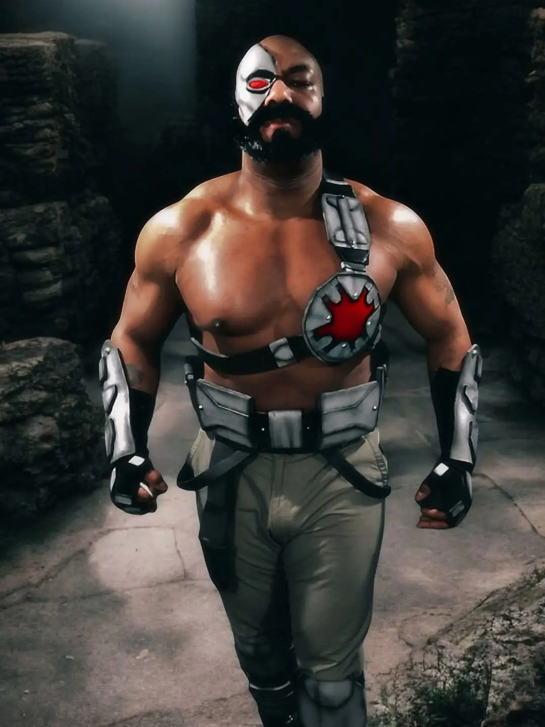 A muscular man with a black beard and a white half-mask over his face, featuring a red glowing eye, stands confidently in a…