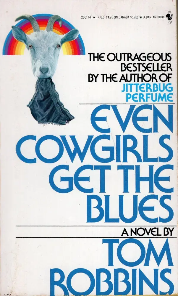 The image shows a vintage book cover featuring a goat with a rainbow behind its head and a black scarf draped over its…