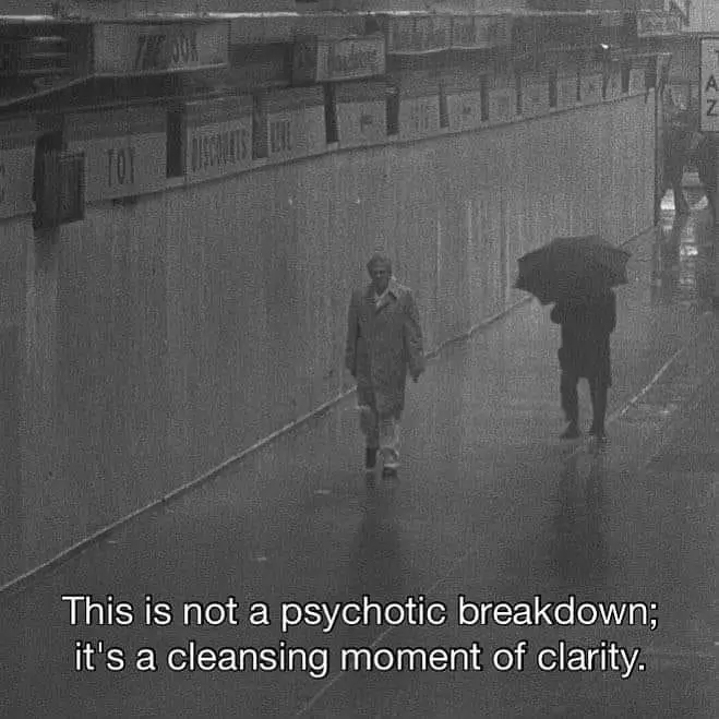 A grainy black-and-white photo shows two people walking down a wet, enclosed urban walkway. One person in the foreground…