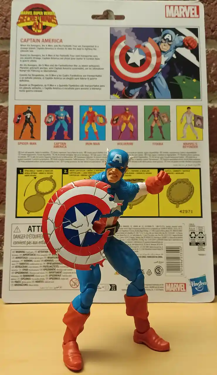 A Captain America action figure stands in front of its packaging, holding a shield visibly cracked with white lines across…