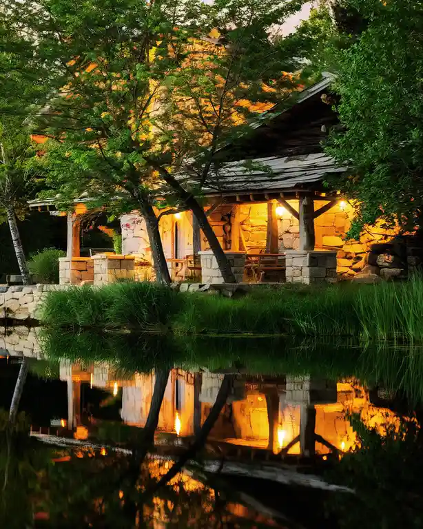 a rustic stone and wood cabin nestled among lush green trees, warmly lit from within, with its entire structure and…
