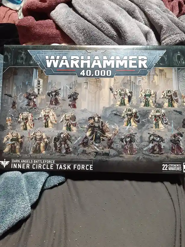 A Warhammer 40,000 box for the Dark Angels Inner Circle Task Force, showing 22 painted miniatures in battle poses on rocky…