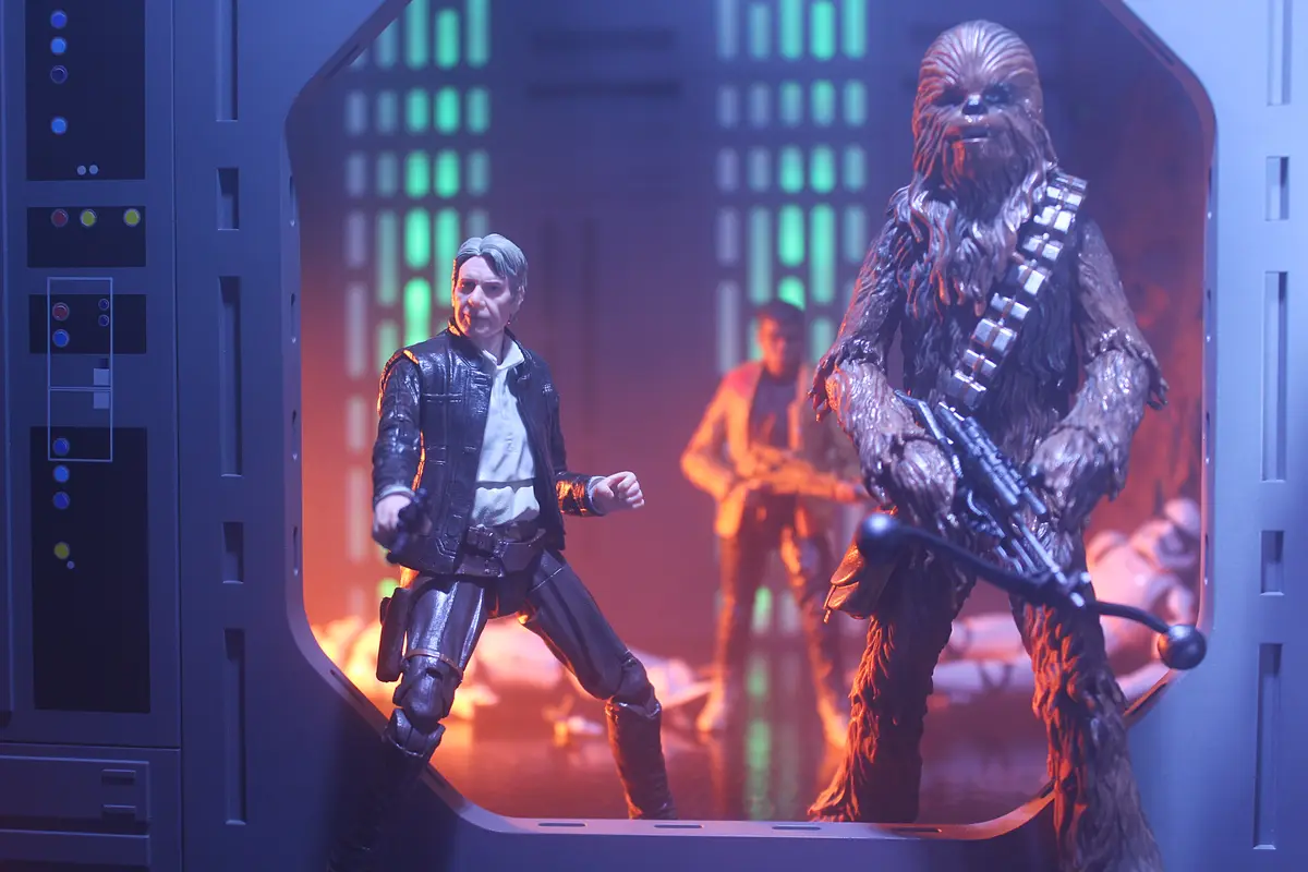 A photo of Star Wars action figures, including Han Solo and Chewbacca, posed in a doorway with a futuristic control panel on…