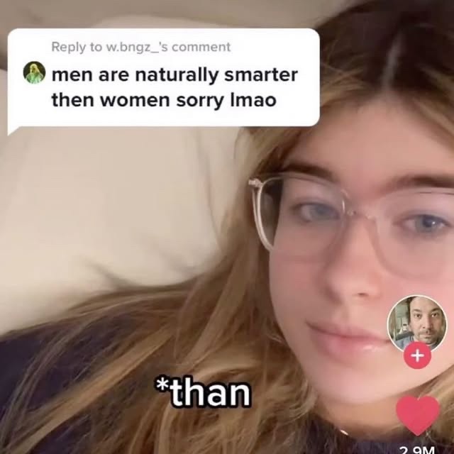 A young woman with glasses lies in bed, looking at the camera with a deadpan expression. A TikTok comment bubble appears…
