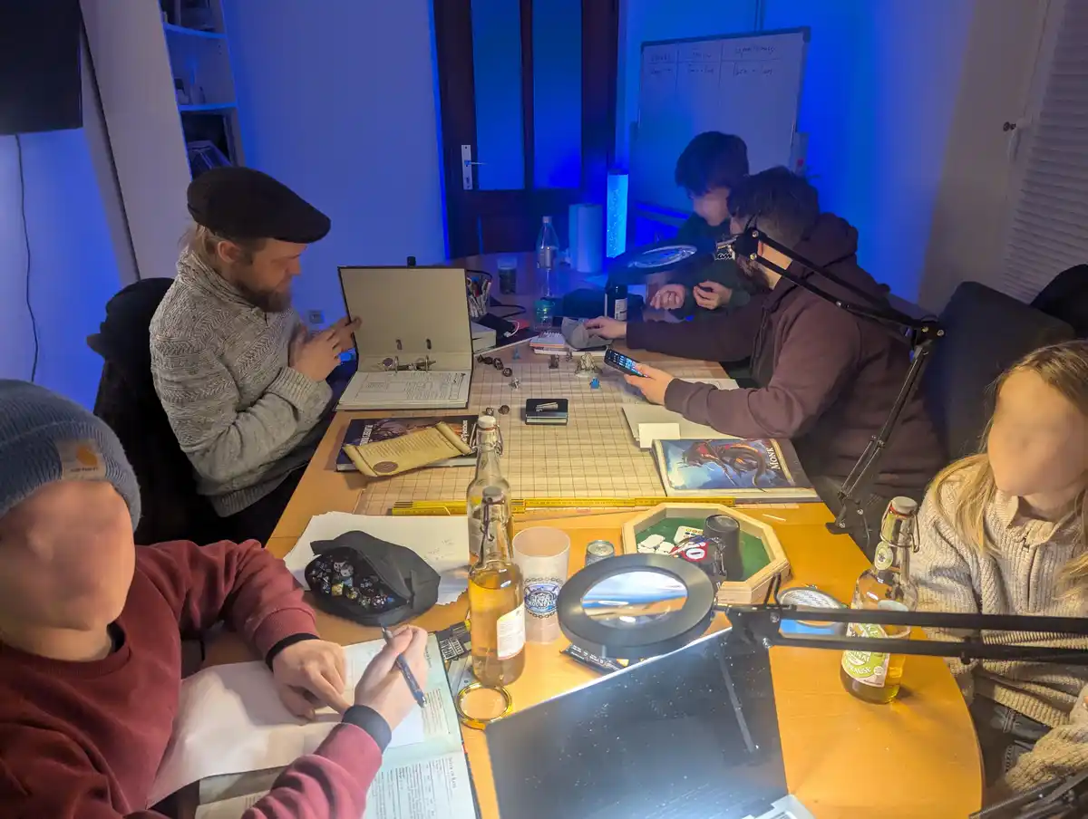 A group of people are gathered around a table engaged in a tabletop role-playing game, surrounded by game books, dice…
