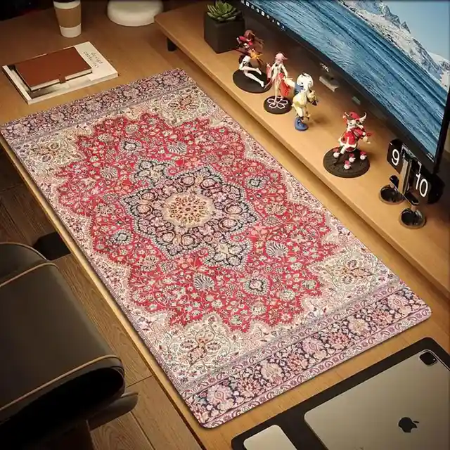 A large, ornate red and beige Persian-style rug patterned mousepad covers most of a wooden desk, with a laptop, figurines…