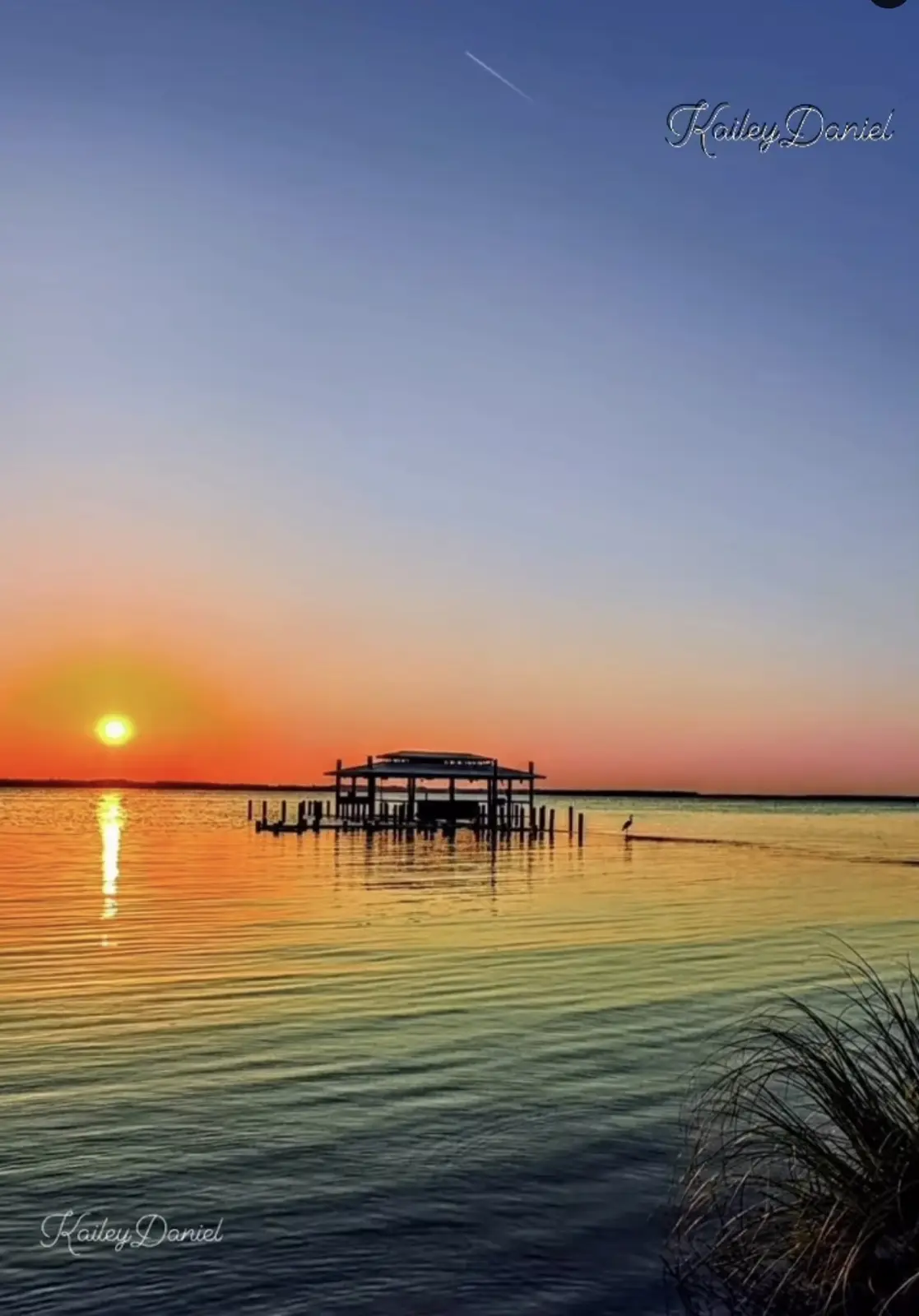 A serene sunset over water with a dock structure and a bird in the distance, overlaid with the text 'i'm not lazy, i'm just…