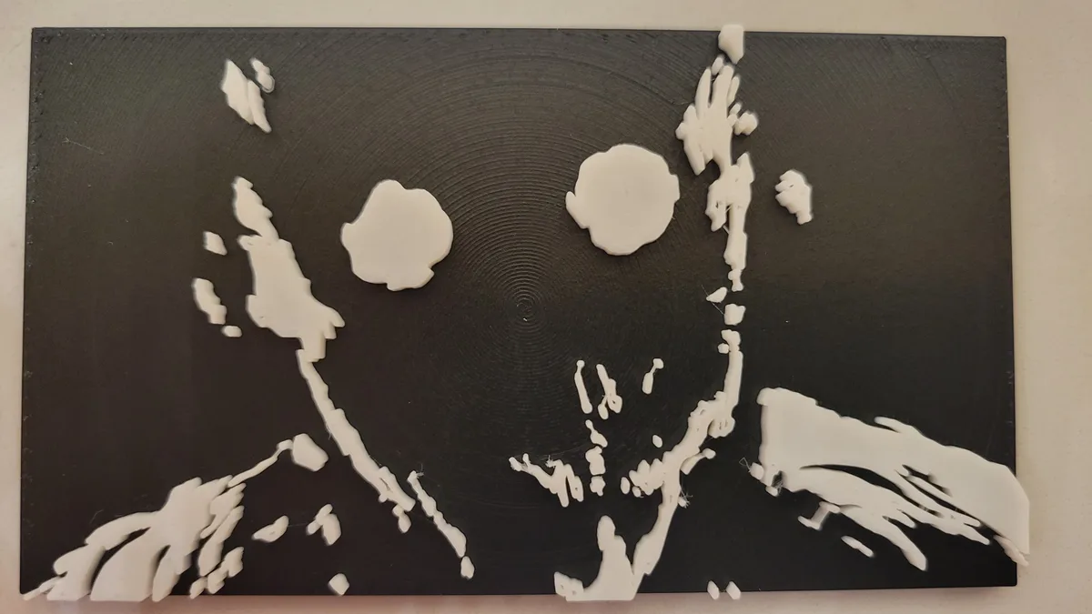 A black, textured surface with white, 3d-printed or extruded material forming an abstract, messy representation resembling…