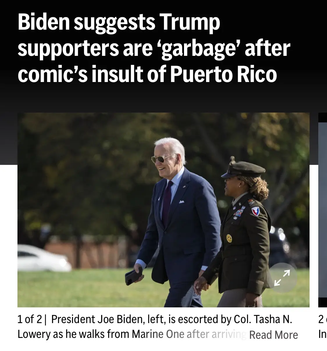 A photo shows President Joe Biden smiling while walking outdoors, holding a phone, accompanied by a military officer in…