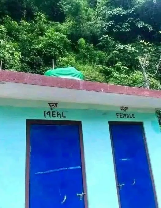 A light blue building with two blue doors, each labeled in English and Devanagari script. The left door is labeled 'MEAL'…