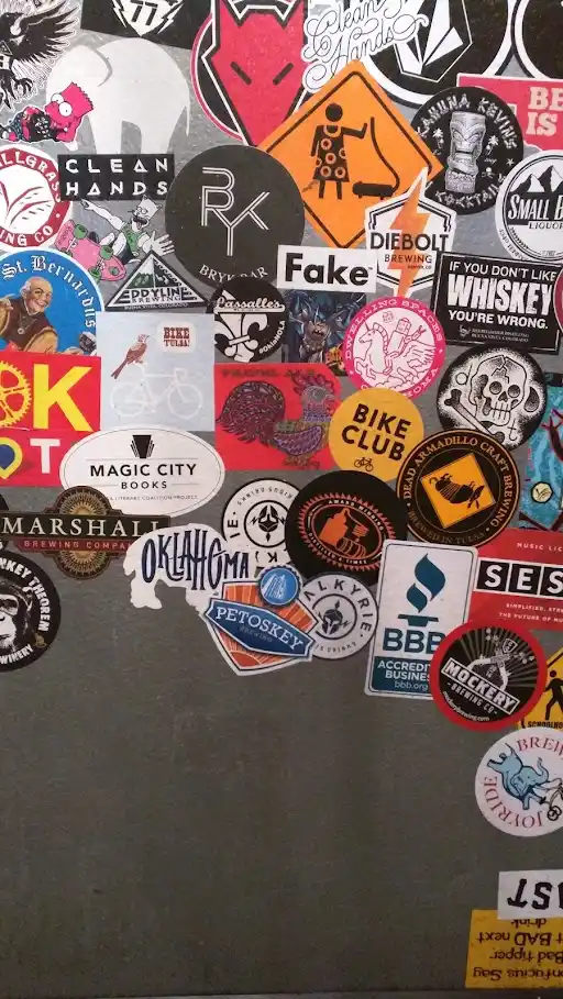 A close-up of a gray surface, likely a refrigerator or metal door, covered in a dense collage of colorful stickers from…