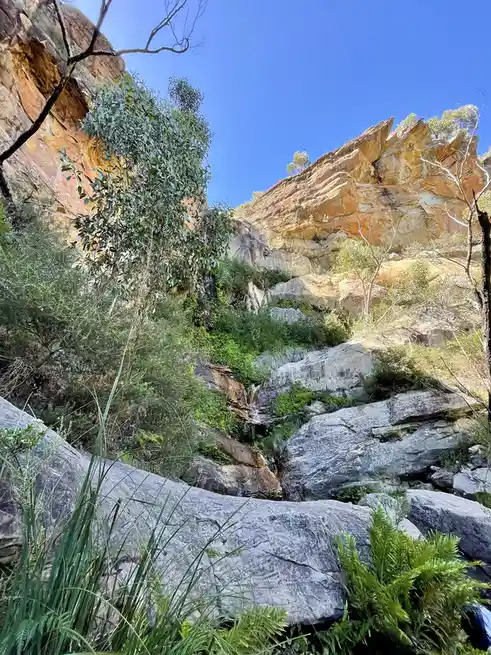 A scenic photo of a rocky, sunlit canyon with green vegetation and a small waterfall, overlaid with the text 'i'm not lazy…