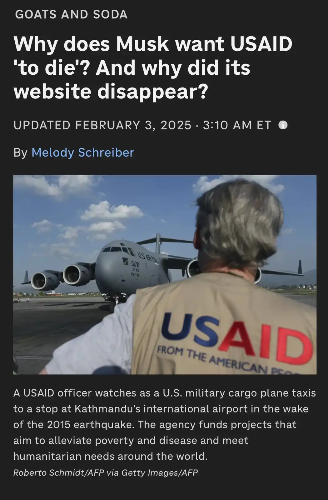 A person wearing a USAID vest stands with their back to the camera, watching a U.S. Air Force cargo plane on an airport…