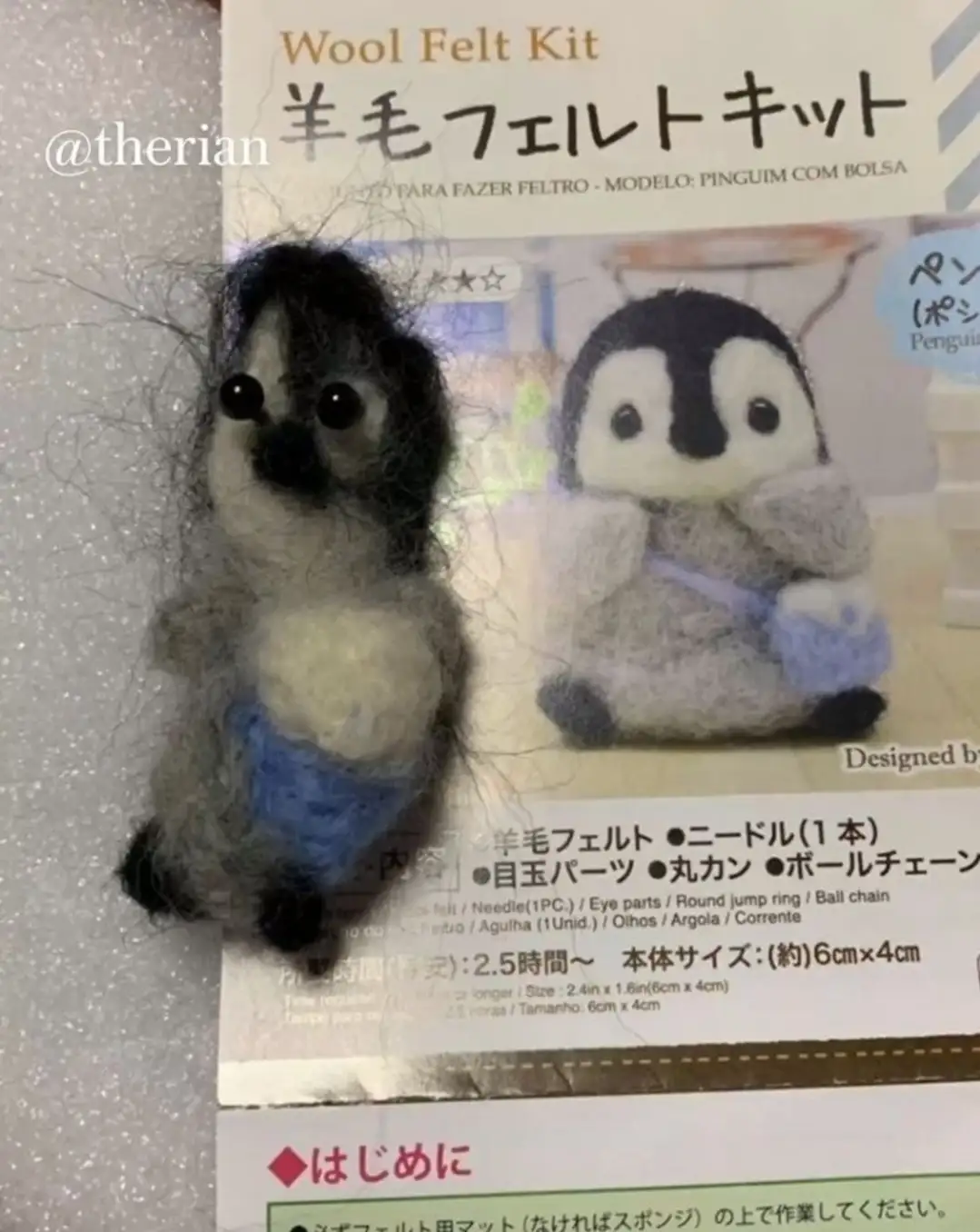 A poorly made wool felt penguin craft sits beside its instruction kit, covered in stray fibers, contrasting with the clean…