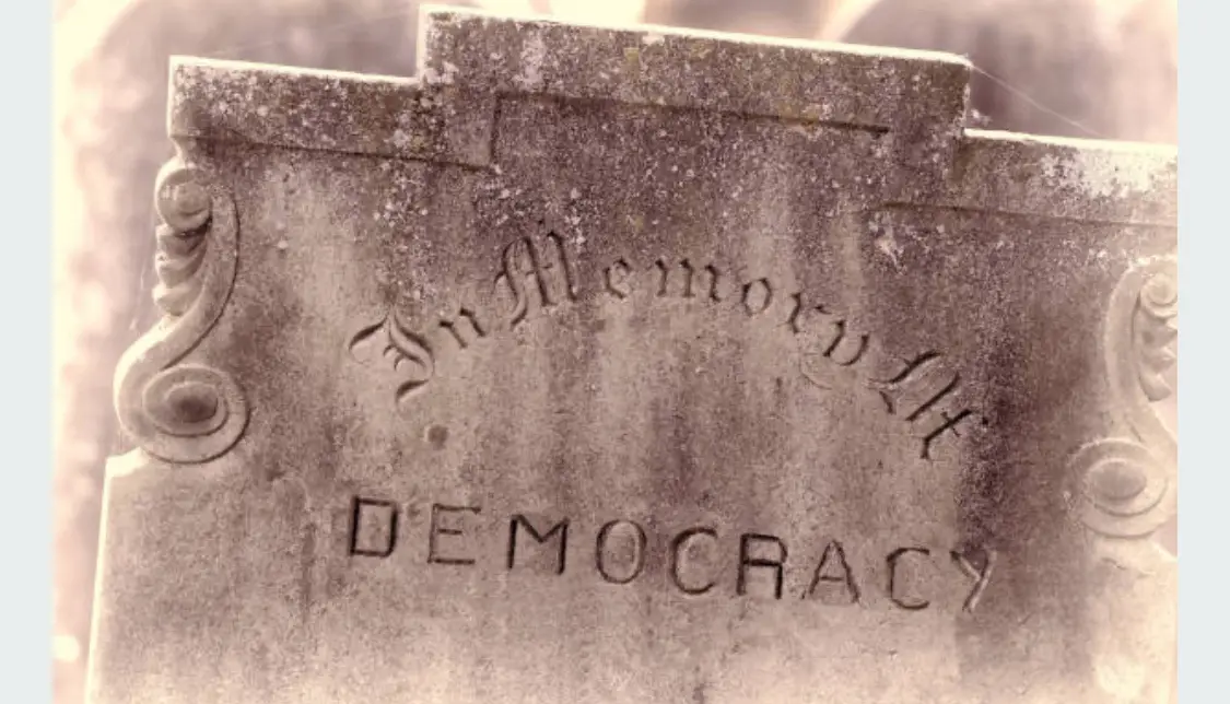 A weathered, moss-covered tombstone with ornate scrollwork on its sides, engraved with the words 'In Memoriam' in cursive…