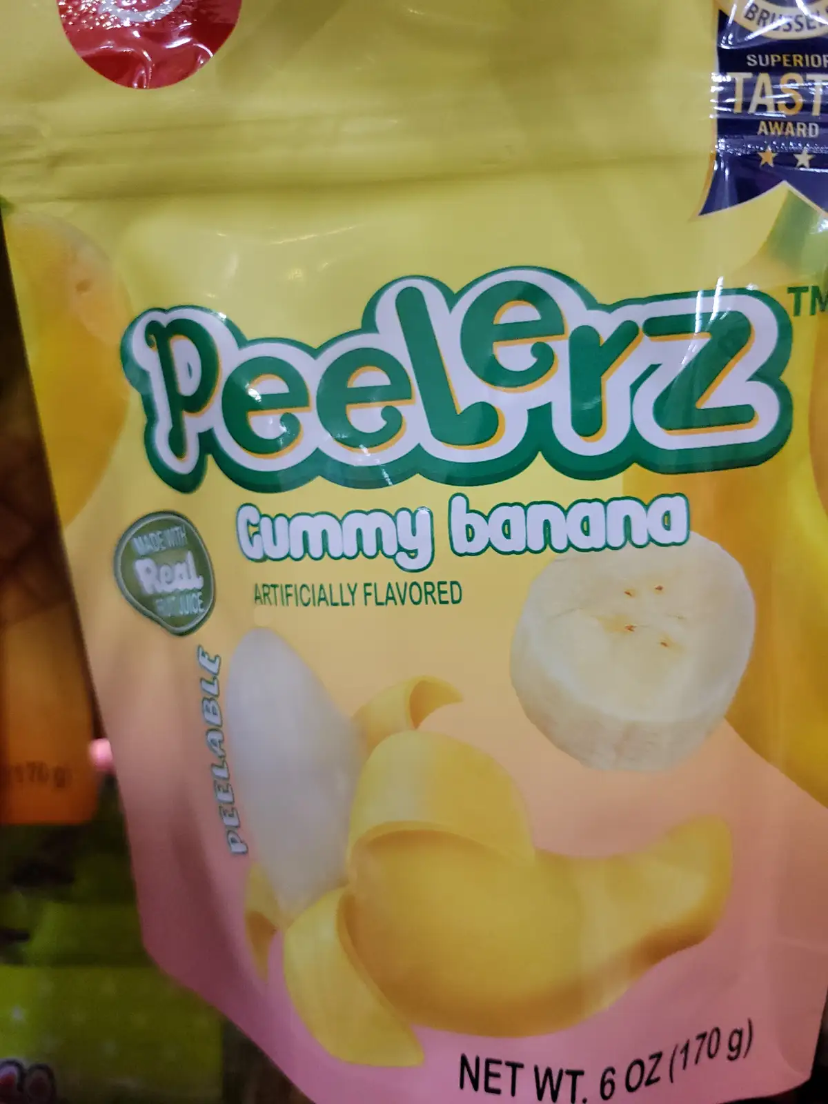 A close-up of a yellow and pink bag of 'PeelErz Gummy banana' candy, which features an image of a peeled banana and text…