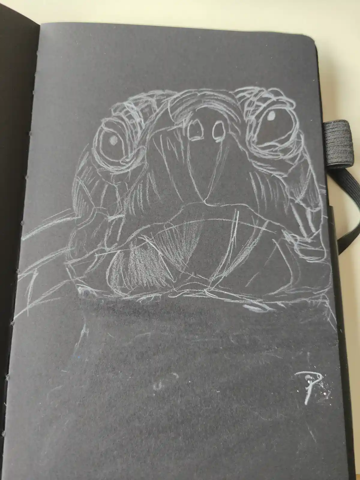 A rough white chalk sketch on a black notebook page depicts a distorted, multi-eyed creature with exaggerated features. The…