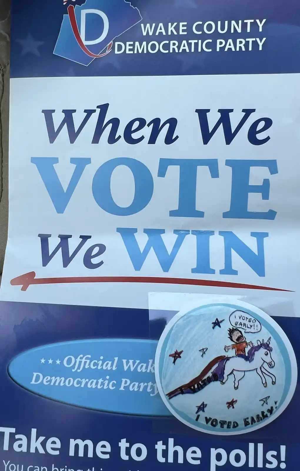 A Wake County Democratic Party poster with the slogan 'When We VOTE We WIN' and an arrow pointing to a child's hand-drawn…
