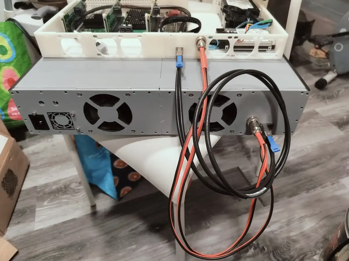 A homemade server setup with a silver metal chassis, visible internal circuit boards, and multiple cables plugged into ports…