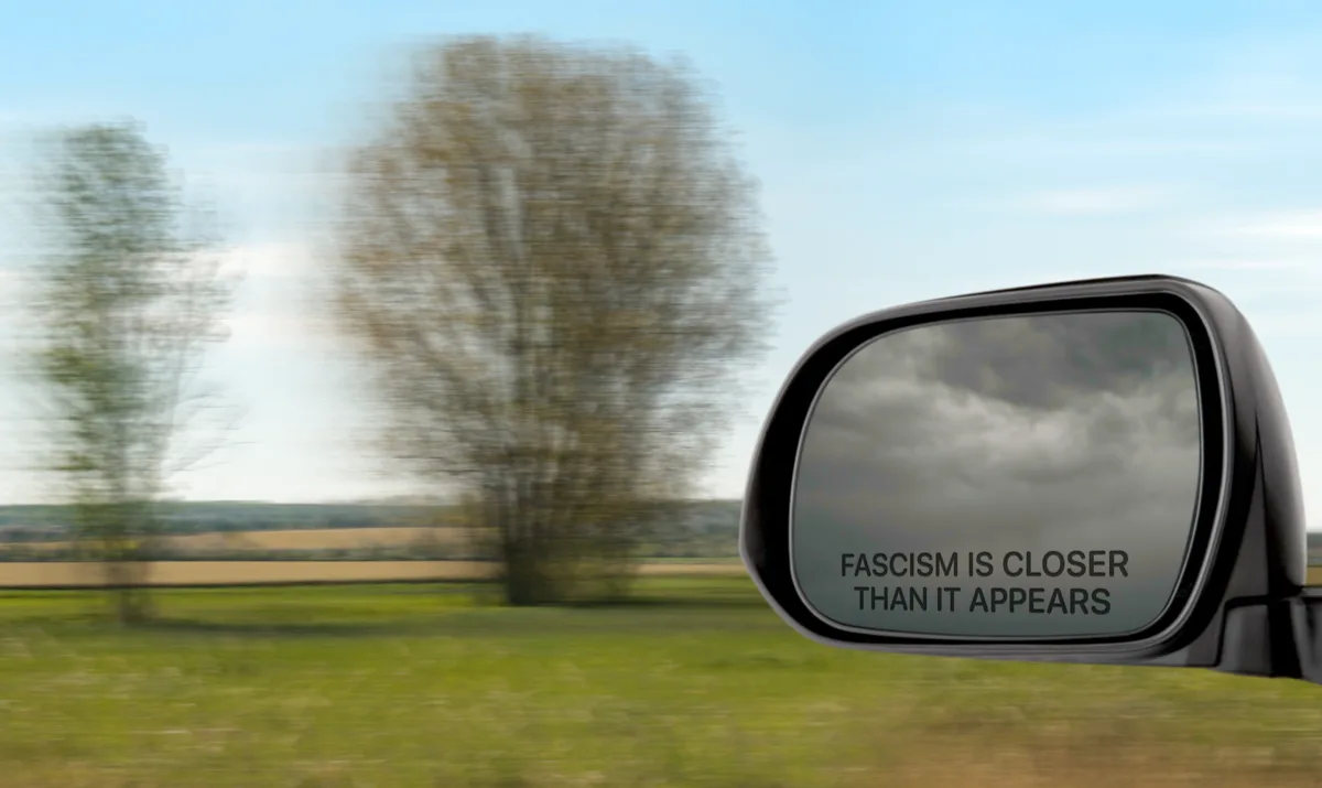 A car's side-view mirror shows a dark, cloudy sky while the outside view is bright and sunny with blurred trees, implying a…