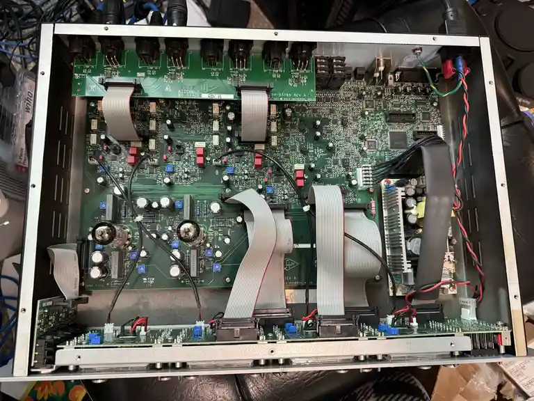 The image shows the open back panel of an audio amplifier revealing its green circuit boards, numerous electronic…