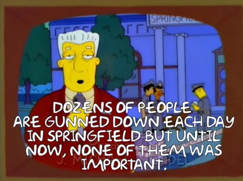 A still from The Simpsons shows a news anchor on a TV screen with a Springfield street scene behind him. The anchor has a…