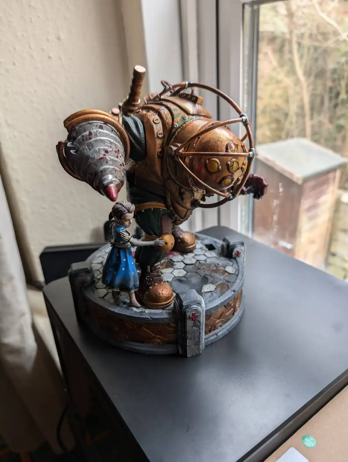 A detailed figurine of a large, armored, steampunk-style robot with a copper helmet and mechanical arm, standing on a…
