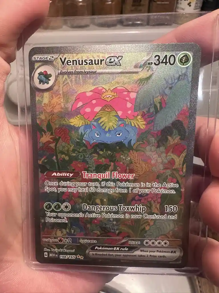 A person holds a Pokémon TCG card of Venusaur EX, which has 340 HP and an ability called 'Tranquil Flower' that lets the…