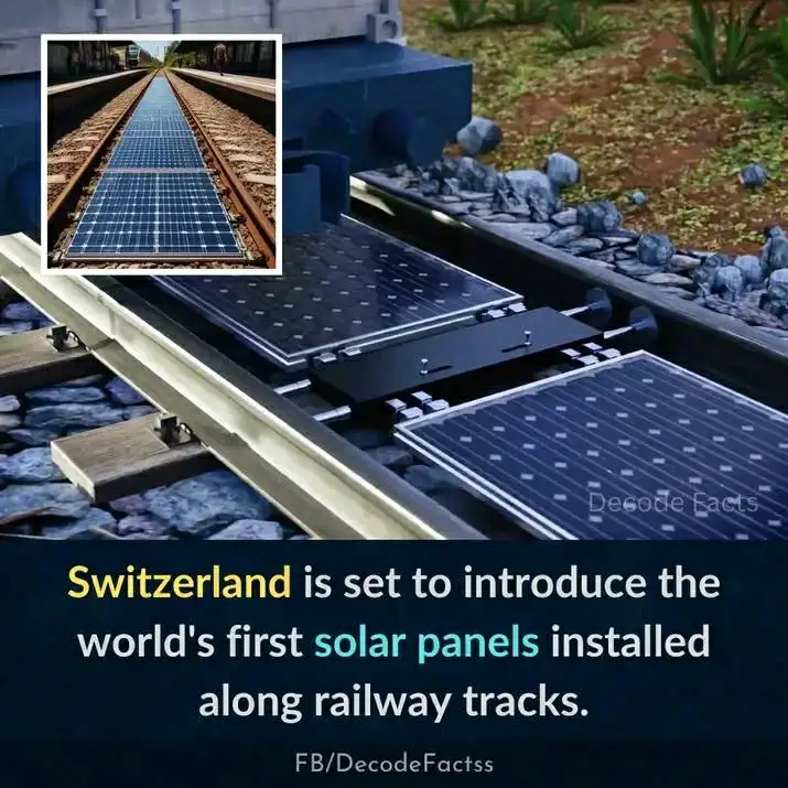 The image shows a close-up of solar panels mounted directly onto railway tracks, with gravel ballast and train…