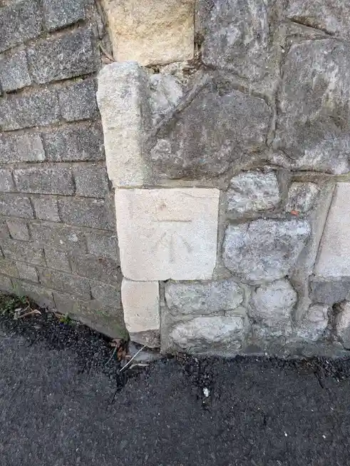 A close-up photo of a corner where two different stone walls meet, one made of uniform grey bricks and the other of…