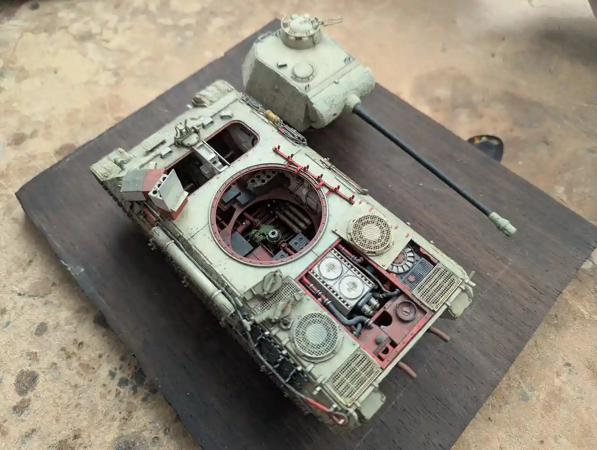 A highly detailed scale model of a military tank, shown with its top and side panels removed to reveal intricate internal…