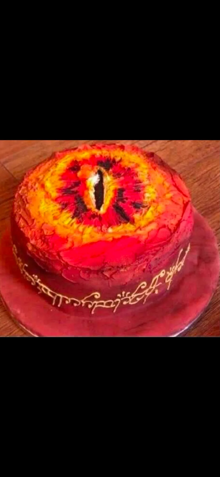 A round cake decorated to resemble the Eye of Sauron from Lord of the Rings, with a fiery red and orange eye design on top…