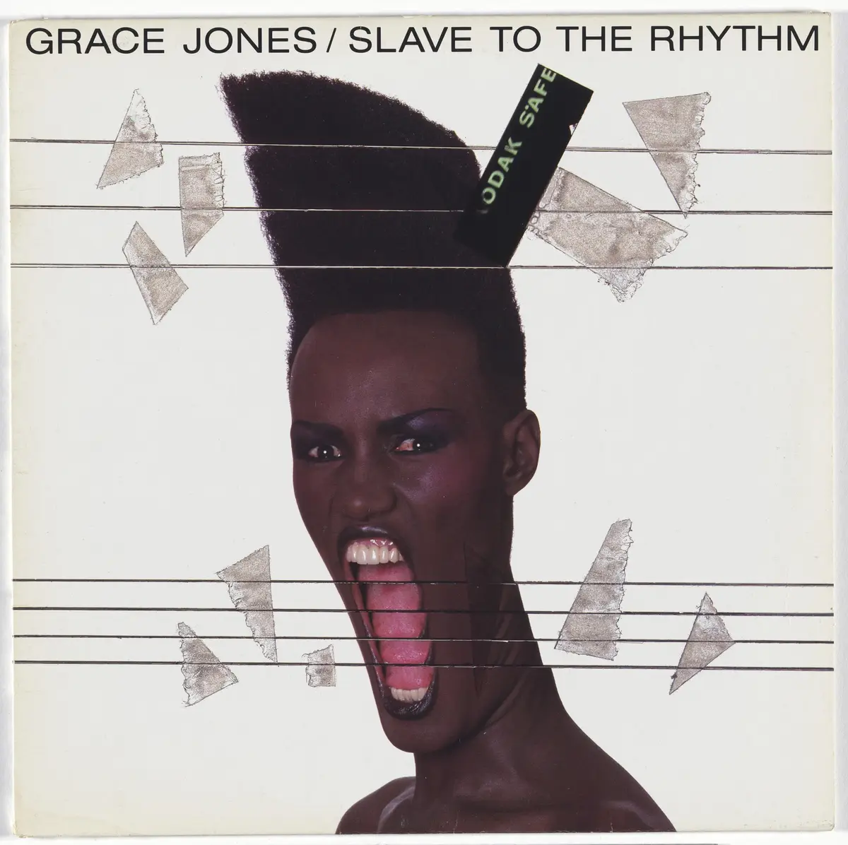 The image is the album cover for Grace Jones' 'Slave to the Rhythm,' featuring a close-up of her with a dramatic, high…