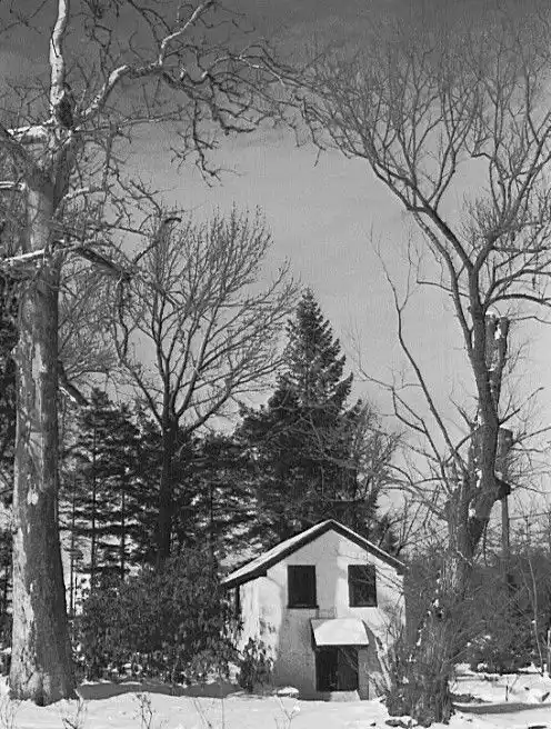 a black-and-white photo of a small, simple house surrounded by snow and bare trees, with the overlaid text 'this is not a…