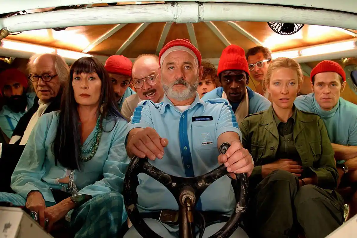 A still from the movie 'The Life Aquatic with Steve Zissou' shows a man in a light blue shirt and red beanie gripping a…