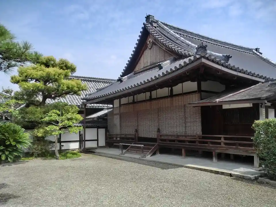 a traditional japanese temple building with a tiled roof and wooden structure, surrounded by a gravel courtyard and…