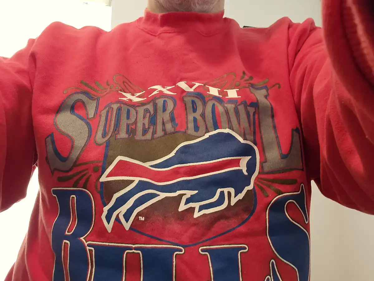 A person wearing a red sweatshirt with 'XXVII SUPER BOWL BUFFALO BILLS' printed on it, featuring the team's charging buffalo…