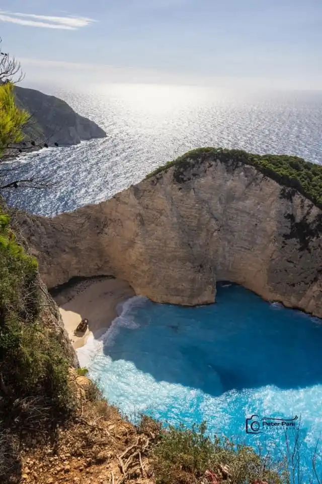 a breathtaking view of Navagio Beach in Zakynthos, Greece, showing turquoise waters, a sandy cove, and a shipwreck on the…