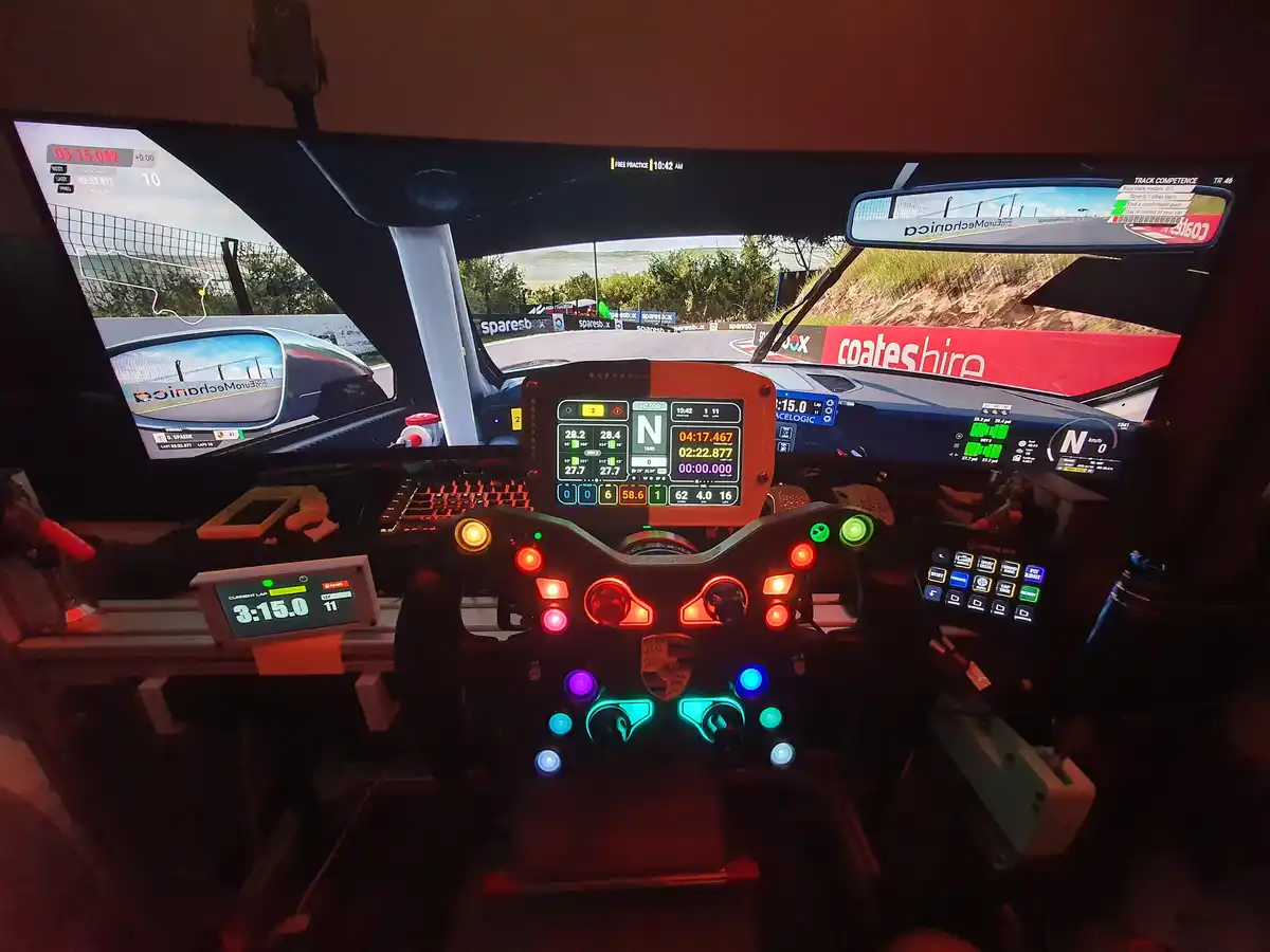 A first-person view from inside a racing simulator setup, showing a detailed dashboard with glowing buttons and a steering…