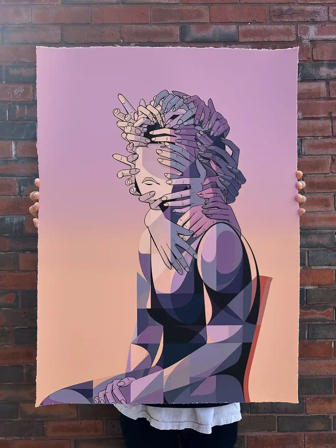 A person holds up a printed artwork depicting a stylized woman with multiple hands covering her face and body, set against a…