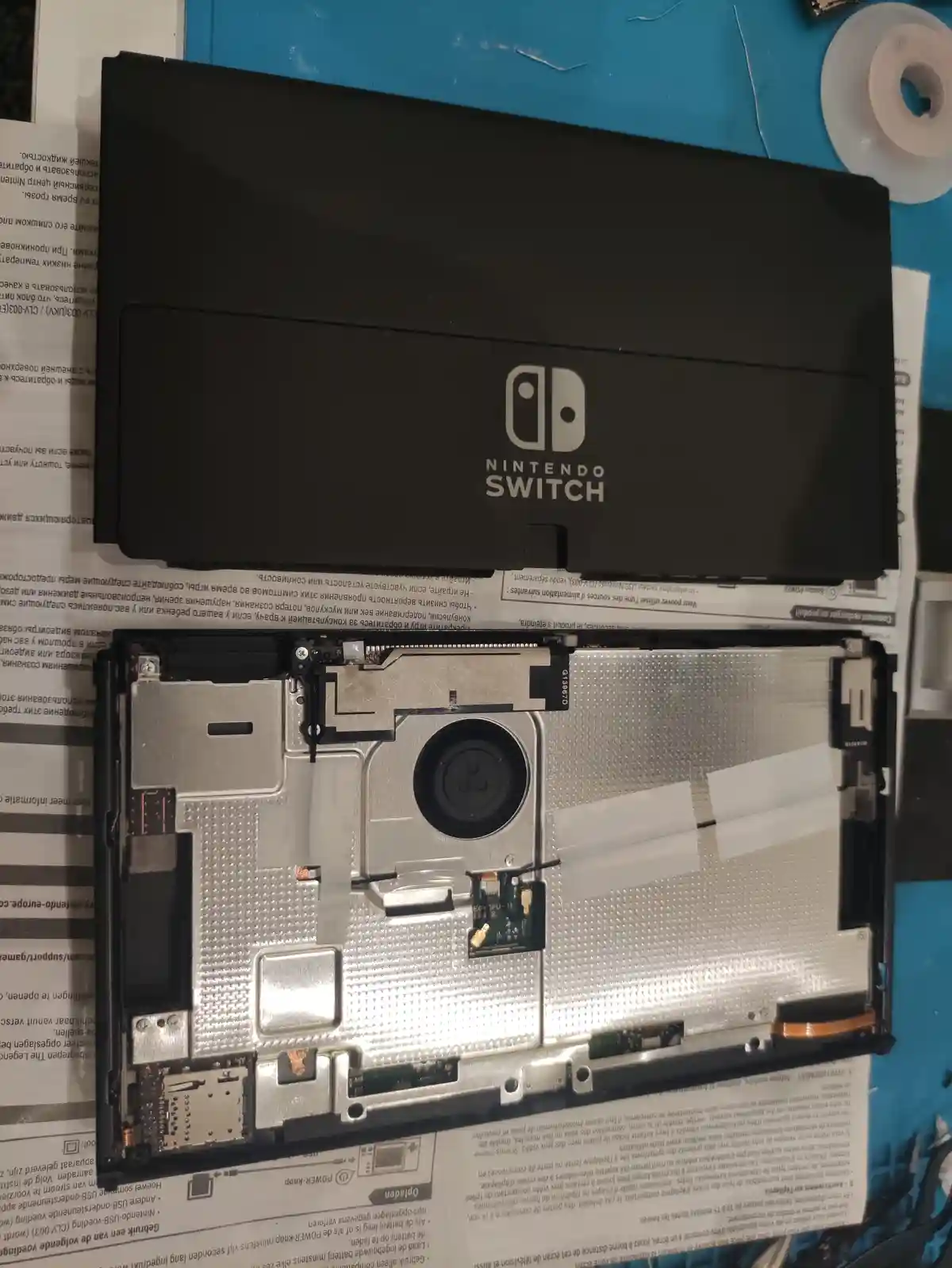 A disassembled Nintendo Switch console is shown with its back panel removed, exposing the internal components including a…