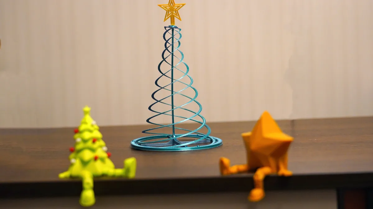 A small green Christmas tree and a yellow star figurine are both sitting on the edge of a wooden surface, looking tired or…