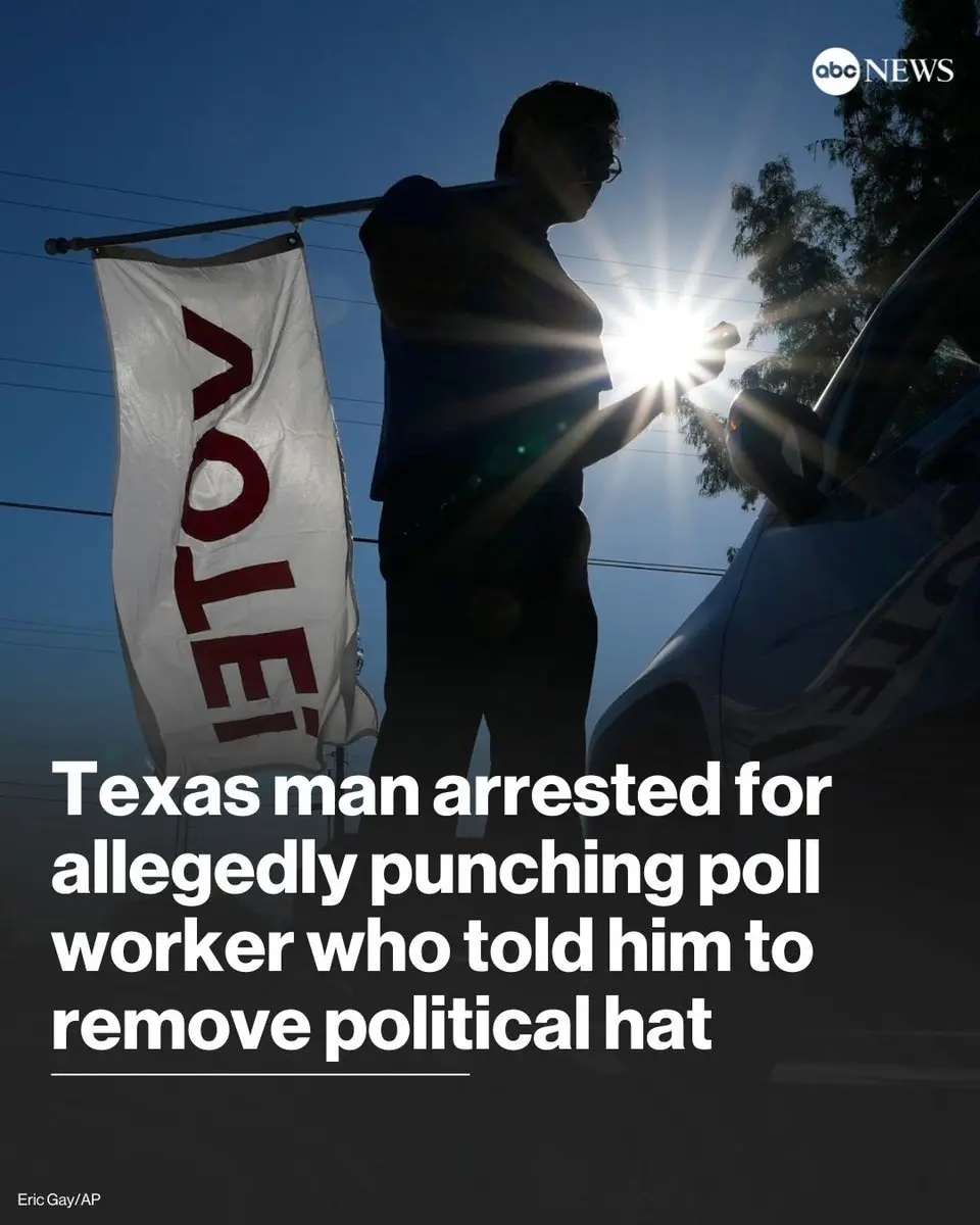 A silhouetted person stands outdoors holding a phone, next to a white banner with red text reading 'VOTE!' and a police car…