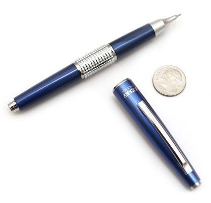 a blue and silver pen with a textured grip section lies next to its cap and a quarter coin on a white background. The…